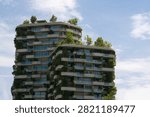 Low angle view of the upper floors of a modern sustainable skyscraper featuring lush vertical gardens, trees, and balconies integrated into the architecture under a blue sky in Rotkreuz, Switzerland. Concept of green architecture, eco-friendly urban design, and sustainable living