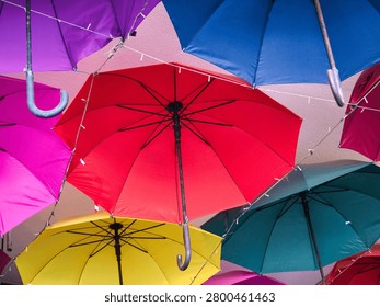 Low angle view of vibrant multicolored umbrellas hanging upside down as a creative outdoor ceiling decoration in a street alley
