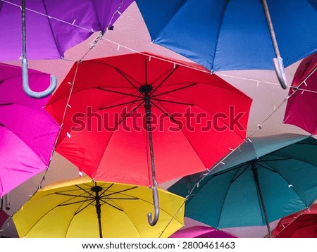 Low angle view of vibrant multicolored umbrellas hanging upside down as a creative outdoor ceiling decoration in a street alley
