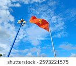 Low angle view of a Vietnamese flag waves in the wind against a backdrop of a blue sky with scattered white clouds.