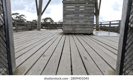 Low angle view of weathered timber decking and railings under an overcast sky.