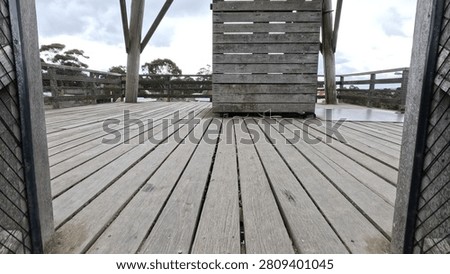 Low angle view of weathered timber decking and railings under an overcast sky.