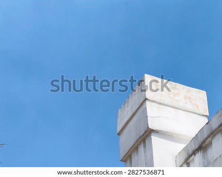 Low angle view of white concrete pillar against clear blue sky for architectural and minimalist background concept.