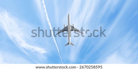 Low angle view of white passenger airplane flying in windy sky.Silky white clouds and a view from below of the airplane.