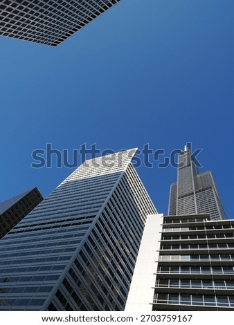 Low angle view of the Willis Tower framed by several sharp, modern architectural structures.
