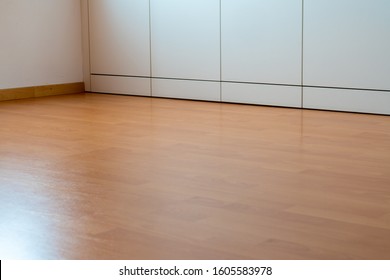 A low angle view of wooden laminate flooring in a bright spacious room with wall-to-wall closet