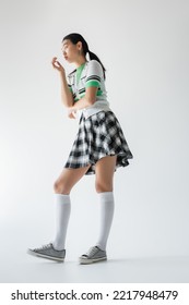 Low Angle View Of Young Asian Woman In Knee Socks Looking Away On Grey Background 