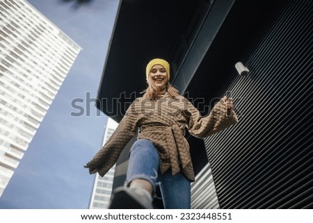 Low angle view of young fashionable woman in a city.