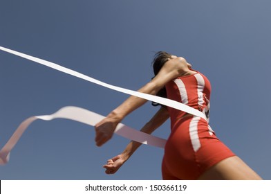 Low angle view of young female athlete crossing finish line against clear blue sky - Shutterstock ID 150366119
