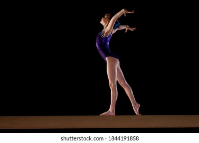 Low Angle View Of A Young Female Gymnast Performing On The Balance Beam.