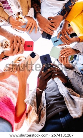 Low angle view of young group of student people using smart phones together outside. Social media and communication lifestyle concept