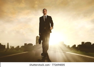 Low angle view of a young male manager carrying a briefcase while walking on the road with skyscraper background - Shutterstock ID 772694005