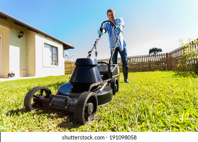 Low Angle View Of Young Man Mowing Lawn At Home