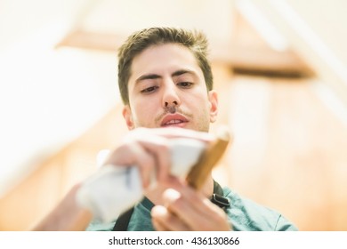 Low angle view of young man crafting wood object, looking down