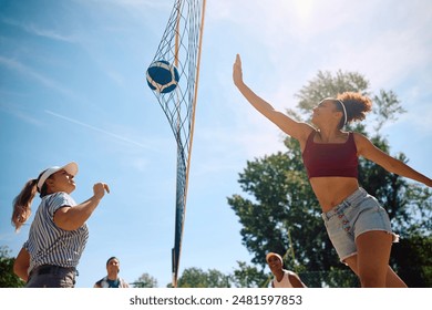 Low angle view of young people playing beach volleyball during summer day. Copy space.  - Powered by Shutterstock