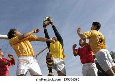 Low Angle View Of Young Players Playing Soccer Against Sky