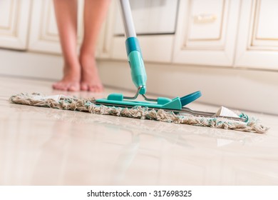 Low Angle View of Young Woman Mopping Kitchen Floor with Focus on Shiny Clean Floor and Mop - Powered by Shutterstock