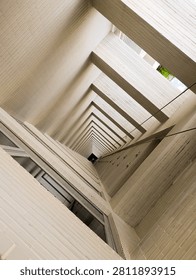 Low angle worm's-eye view of a modern building's ventilation shaft, showing clean geometric lines, white tiled walls, and a dramatic vanishing point perspective.