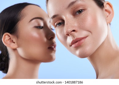 Low Angle Of Young Pretty Asian And Caucasian Ladies With Different Types Of Skin Standing Near Each Other And Looking At Camera In Studio. Beauty, Facial Treatment And Spa Concept