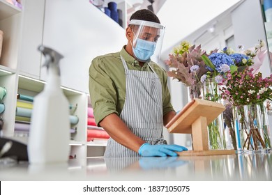 Low Angle Of Young Shop Assistant Standing At Counter And Wearing Mask And Protective Glass For Care During Pandemic