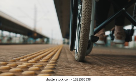 Low angle, young woman spinning the wheels of the wheelchair on the train station. High quality photo