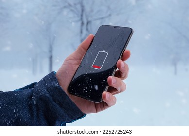 Low battery on smartphone in man hand. Winter, cold time.  Concept of faster battery discharge at low temperatures - Powered by Shutterstock