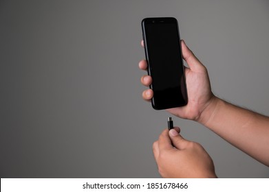 Low battery of smartphone. Male hands holding smartphone and charging with cable line. Cell phone connects plug of charger. - Powered by Shutterstock