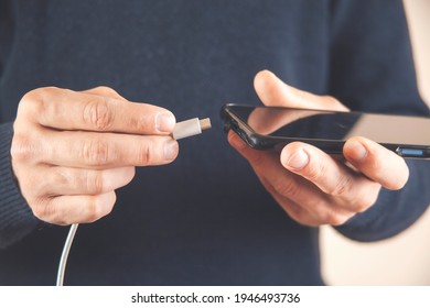 Low Battery Of Smartphone. Male Hands Holding Smartphone And Charging With Cable Line. Cell Phone Connects Plug Of Charger.