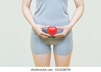 low body of woman standing over isolated gray background holding a red heart .health care concept.