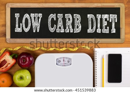 LOW CARB DIET Fitness and weight loss concept, dumbbells, white scale, fruit and tape measure on a wooden table, top view, free copy space, phone