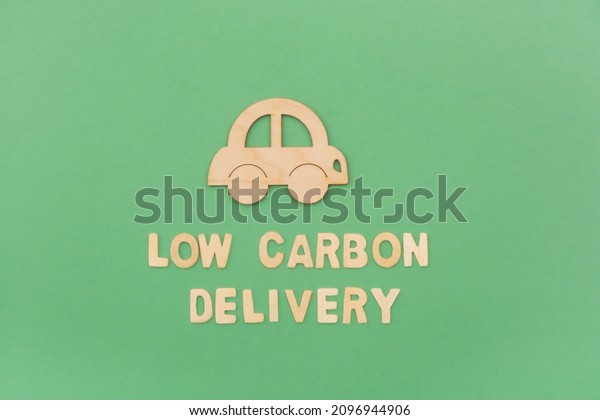 Low carbon\
delivery concept, eco transport, vehicle. Wooden letters on green\
background, flatly.Top view, copy\
space.