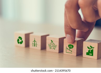 Low carbon,carbon neutral concept. Net zero greenhouse gas emissions target. Climate neutral long term strategy. Hand put wooden cubes with decrease carbon emission icon and green icon. Green banner. - Shutterstock ID 2114395670
