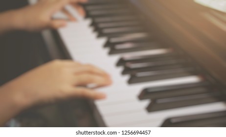 Low contrast, low light, blurry shot of Asian little girl practicing piano lesson at home for use as background with space for copy space - Powered by Shutterstock