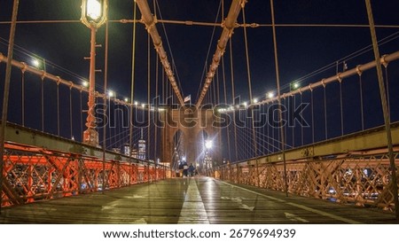 Low down view looking across the Brooklyn Bridge from the walkway platform at night. 