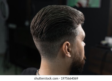 Low fade machine haircut for handsome bearded man in barbershop. Hair cut with a smooth transition