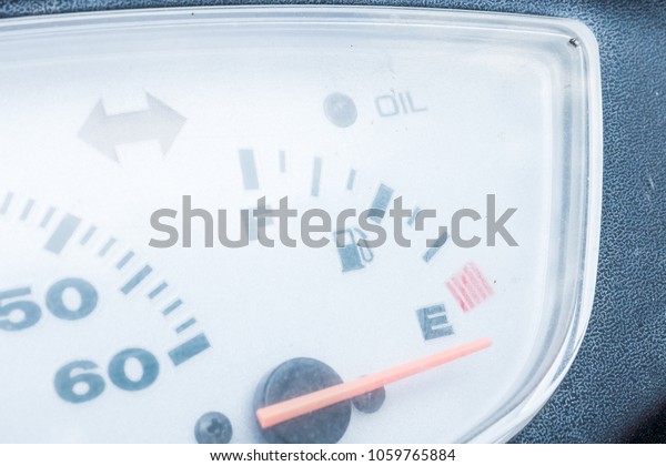 Low fuel sign with red indicator on grey\
background. Old and dirty fuel\
gauge.