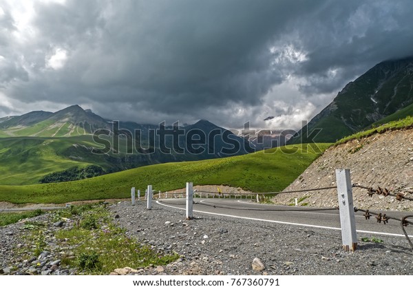 Low gray clouds over\
mountain road