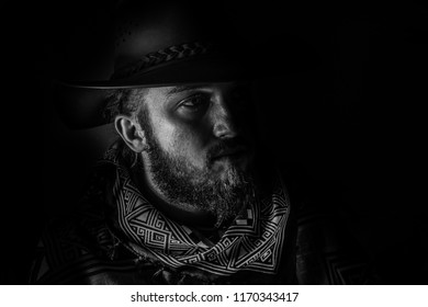 Low key, black and white male cowboy in a poncho portrait