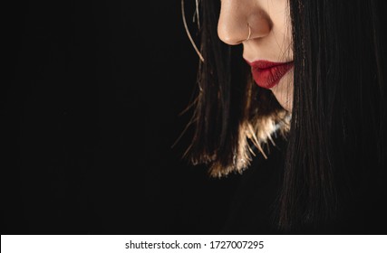 Low key close up of young woman with nose piercings
