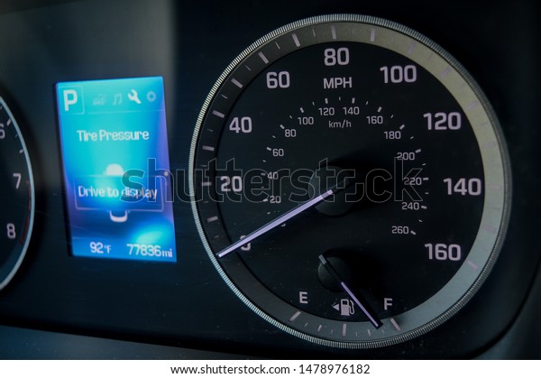 low key\
image of a cars blue and grey\
speedometer.