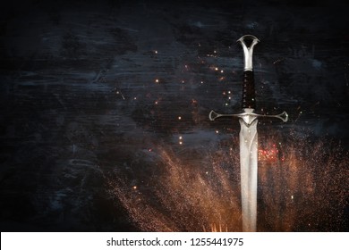 low key image of silver sword with fire sparks. fantasy medieval period