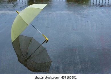 Low key mirror reflection Yellow umbrella on the wet floor back ground