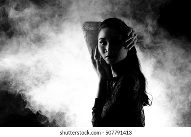 Low Key Portrait Of Slim Healthy Woman In Black Background With Fog And Light From Back, Sexy Pose S Curve With Short Pants And Shadow, Black And White Concept, Copy Space For Text