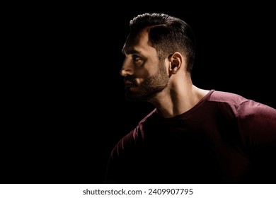 Low key portrait of young man with beard on dark background, Dramatic ambiance: Young man's portrait exudes intensity in low-key darkness - Powered by Shutterstock