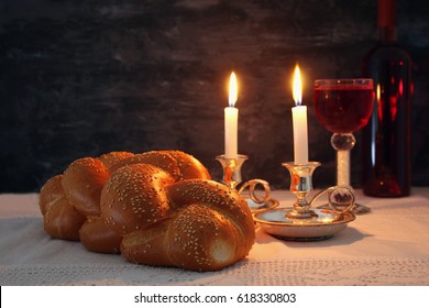 Low key shabbat image. challah bread, shabbat wine and candles on wooden table