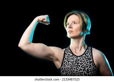 Low Key Studio Portrait Of A 35 Year Old White Woman Showing Her Biceps