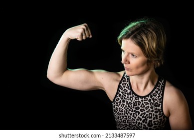 Low Key Studio Portrait Of A 35 Year Old White Woman Showing Her Biceps