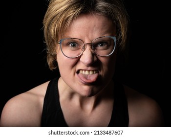 Low Key Studio Portrait Of A 35 Year Old White Woman Pulling Her Tongue