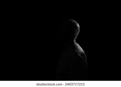 Low light portrait of bearded, bald man. Dark background - Powered by Shutterstock