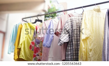 low light, soft shot of colorful washed household clothes remaining not dried on stainless steel rail at urban condominium balcony on rainy day